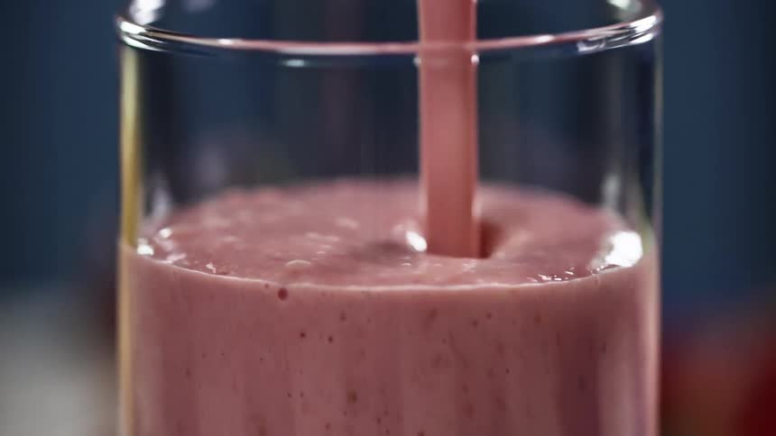 Strawberry smoothie is poured into a glass