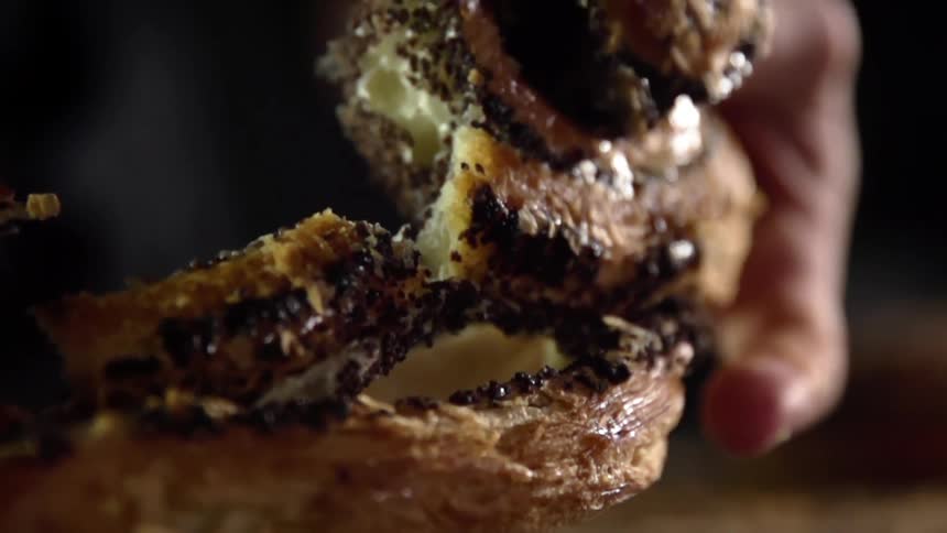 A white man pulls a cinnamon bun apart