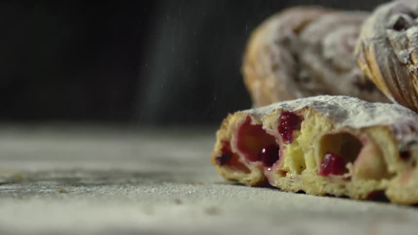 Powdered sugar is dusted onto pastries filled with strawberry jam