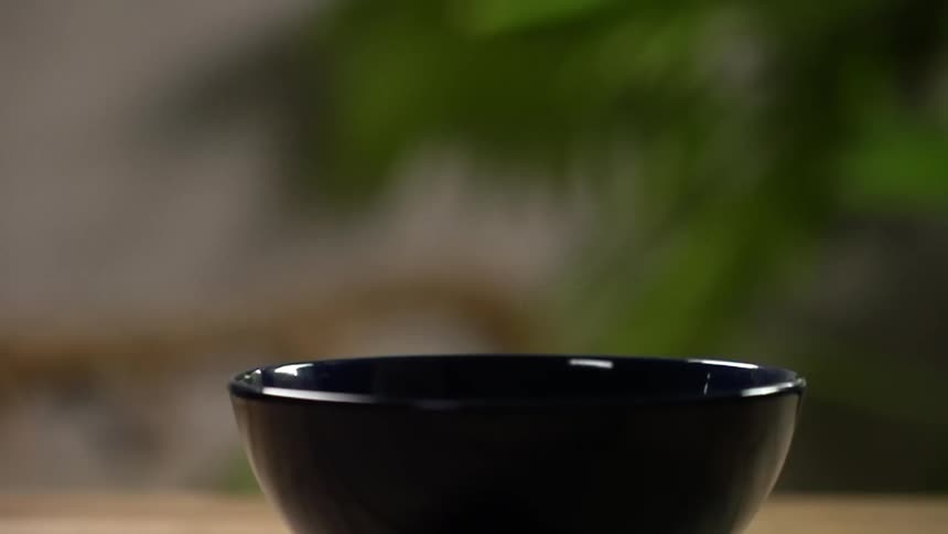 Sliced lettuce falls into a black bowl on the countertop
