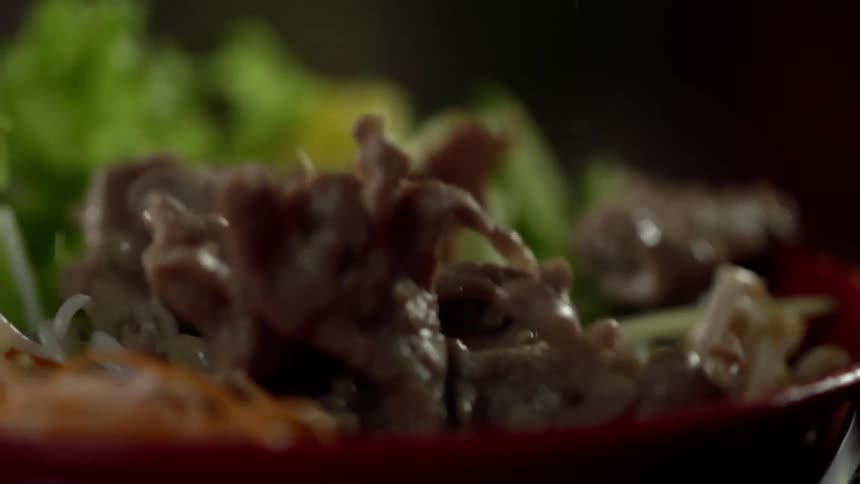 Meat being added to a bowl of vegetables