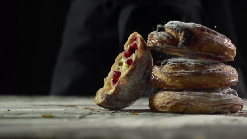 A bread pastry falls on a pile of other pastries