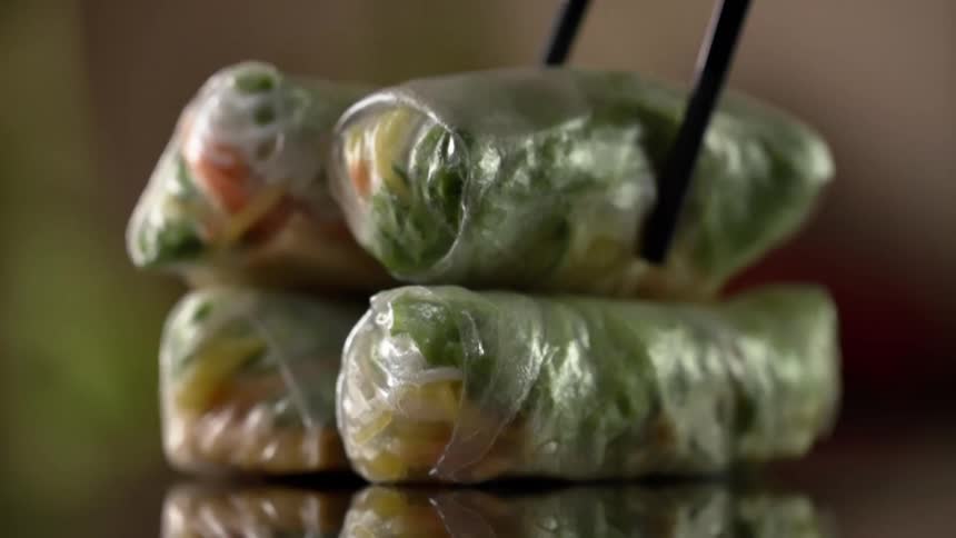 An egg roll is lifted from the stack
