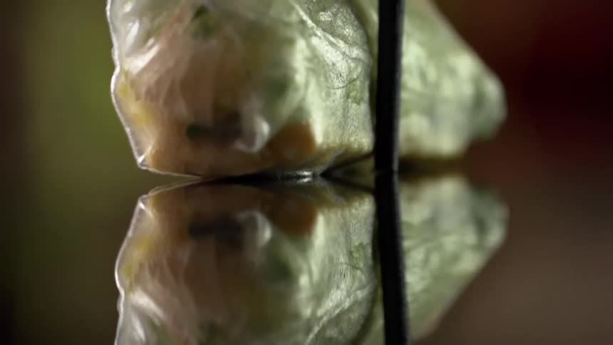 Vegetarian translucent wrapper picked up from a reflective surface with chopsticks