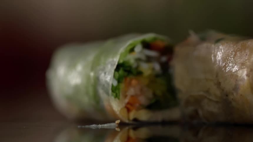 Vegetable sushi roll sliced and rolling over a reflective surface