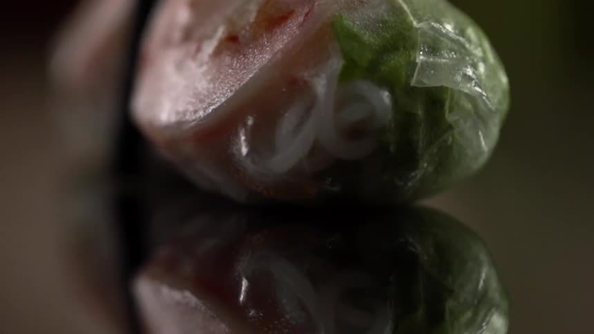 Vegetarian translucent wrap filled wit noodles over a reflective surface