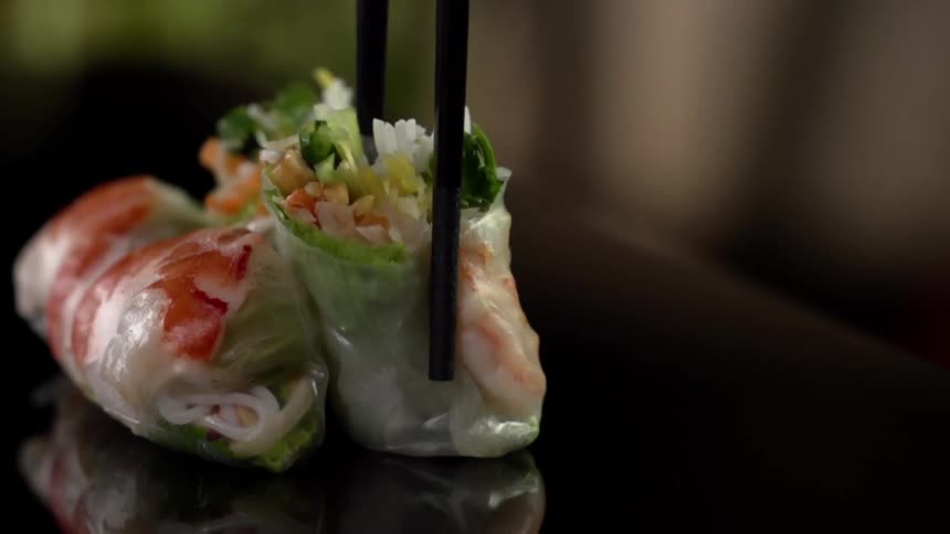 A cut half of a vegetable filled spring roll is placed on its end next to two other rolls