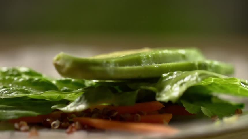 Sliced avocado is added to a salad with lettuce and carrots