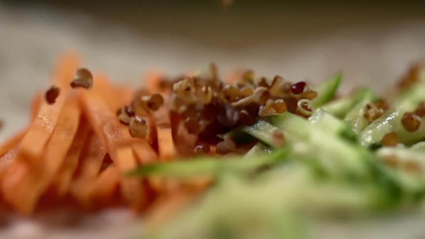 Cooked grains fall over a bed of sliced carrots and cucumbers