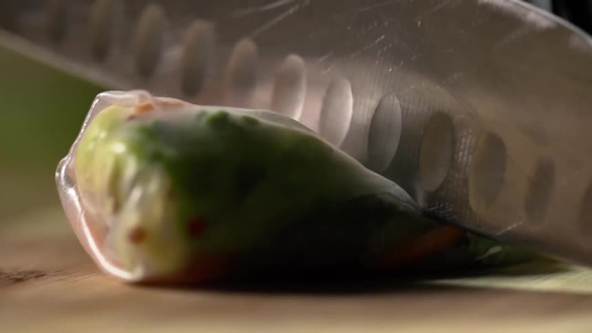 A serrated knife slices through a piece of food