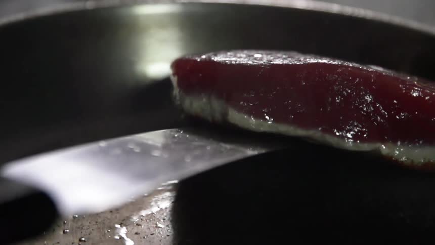 A spatula lifts a piece of meat out of a cooking pan