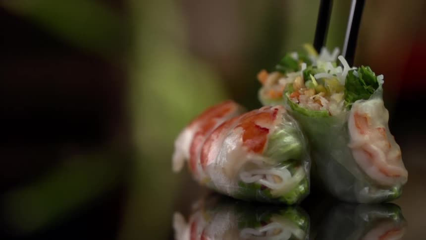 A piece of food is picked up with chop sticks