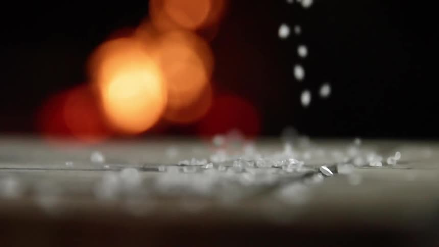 Salt crystals are sprinkled atop a cutting board while an open flame flickers in the background