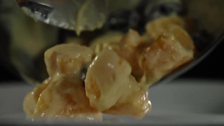 A spoon drops a bit of sticky food onto a plate