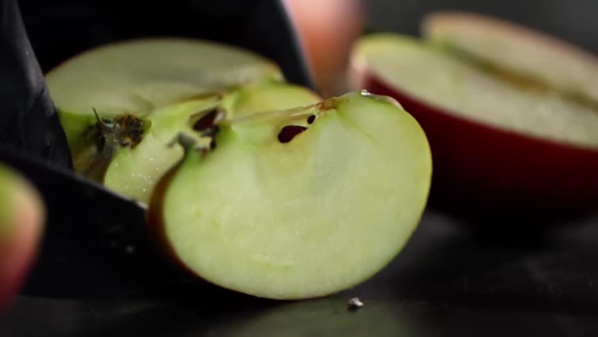 Close up of hands with black gloves cutting an apple on the counter