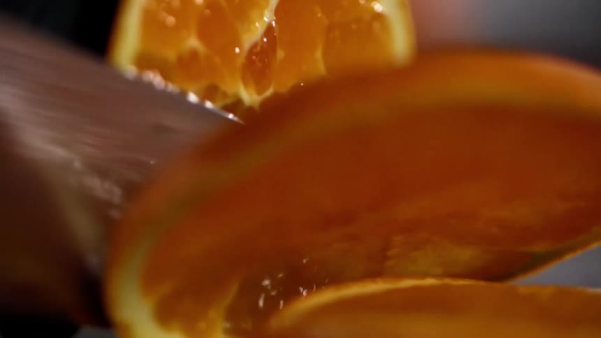 Close up of hands wearing black gloves slicing a juicy grapefruit