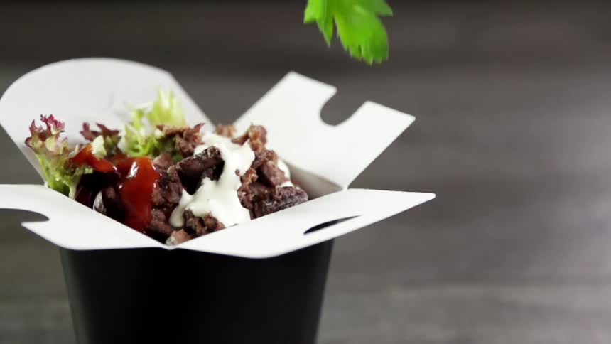 Garnish falls onto food in a takeout box