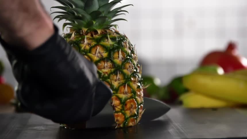 Sharp knife slicing side of a pineapple
