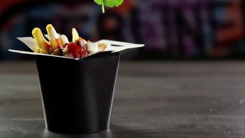 A garnish is placed on a box of french fries