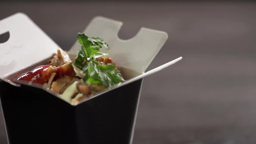 Garnish is added to food in a takeout container