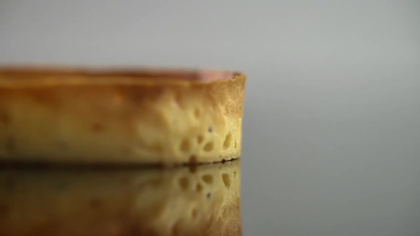 A golden brown round bread drops down onto a mirrored surface
