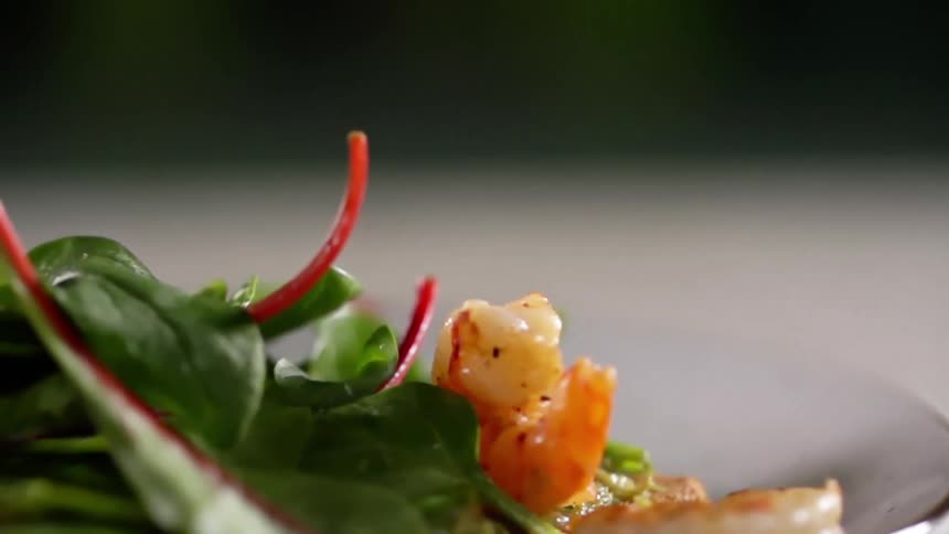Close up of a shrimp falling on a salad plate
