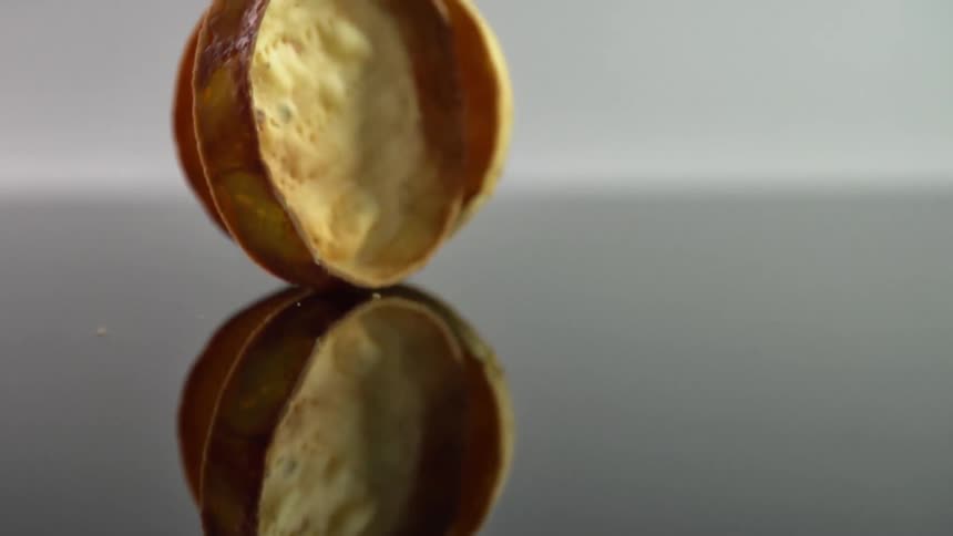 Round food rolls over a reflective surface