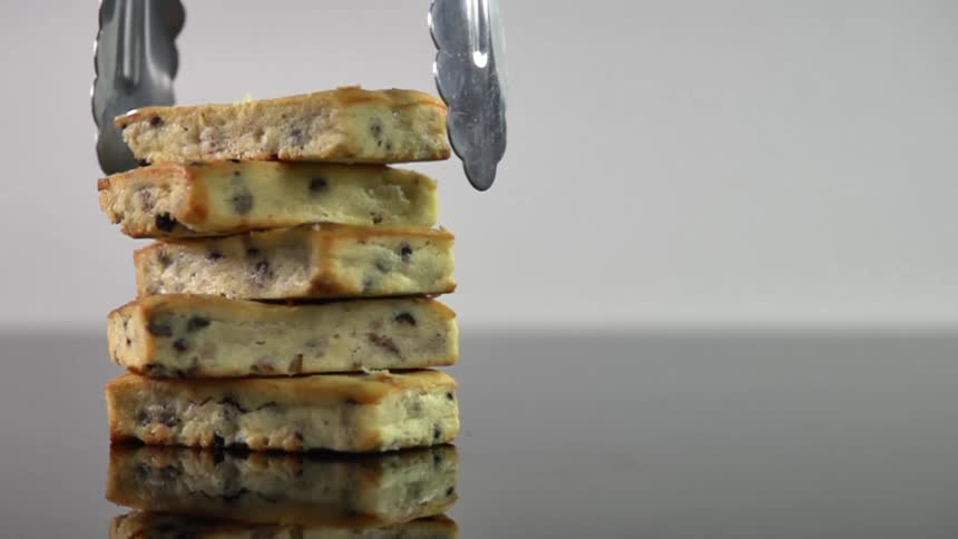 Metallic pliers picks the top pastry in a pile