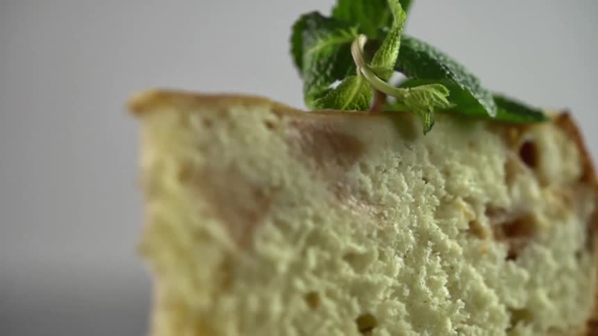 A cheesecake on a glass table with a leafy vegetable on top of it