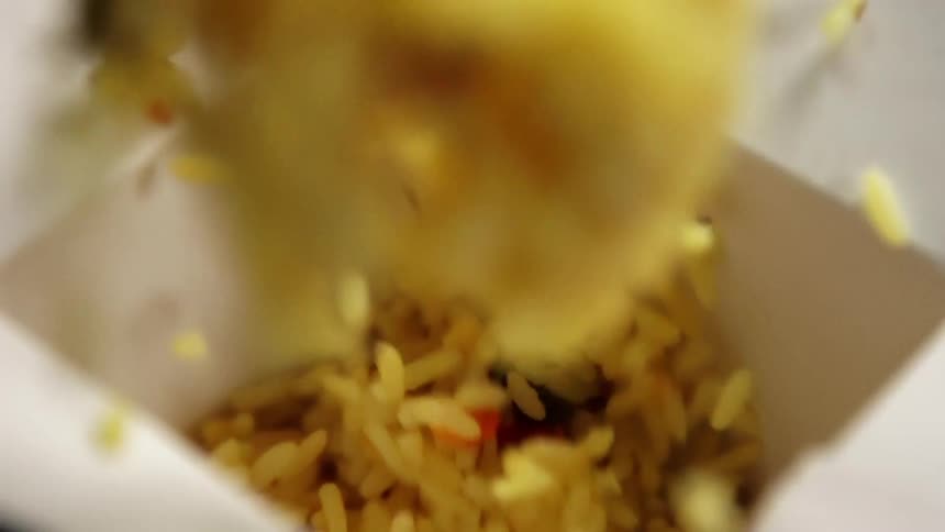 Vegetables and rice fall into a container on a table