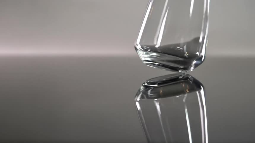 An empty glass is spun on a reflective surface