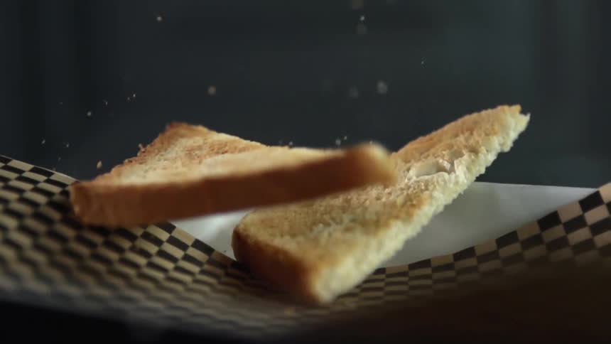 Slices of toasted white bread fall over checkered paper on a tray