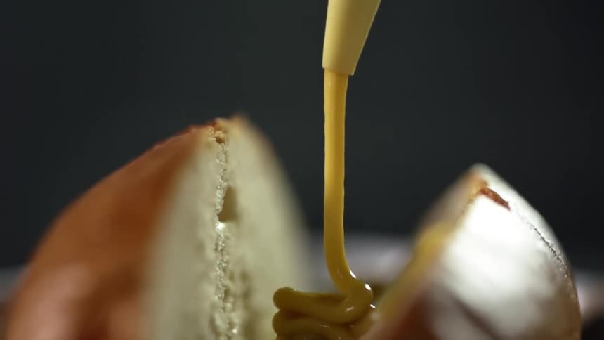 Mustard is being poured into the bun