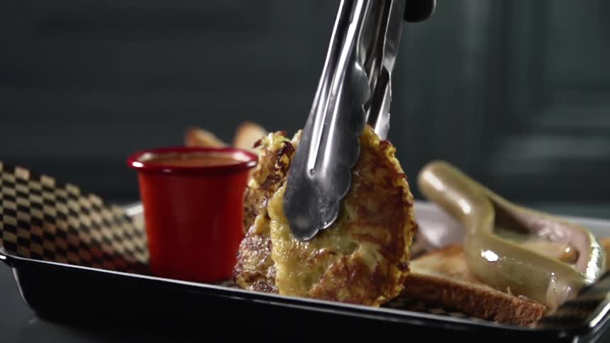 Tongs add food to paper lined tray next to sauce cup