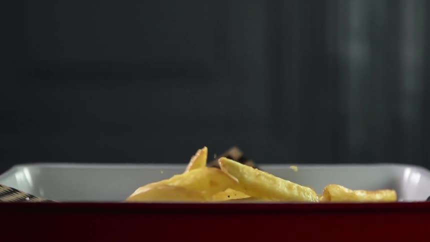 Long thin french fries fall in a tray