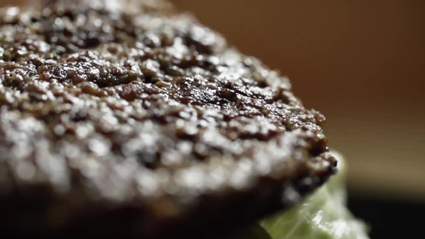 A burger patty is placed on the lettuce and tomato