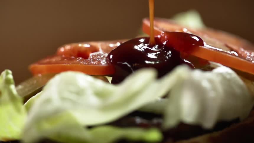 Barbecue sauce pours on a hamburger