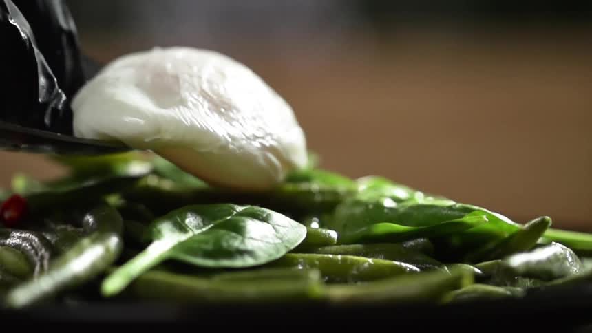 A poached egg is placed on the string beans