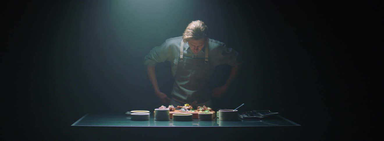 A chef is preparing food in a dark kitchen
