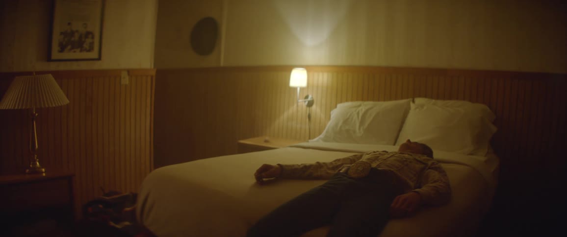 A man sits on a motel bed