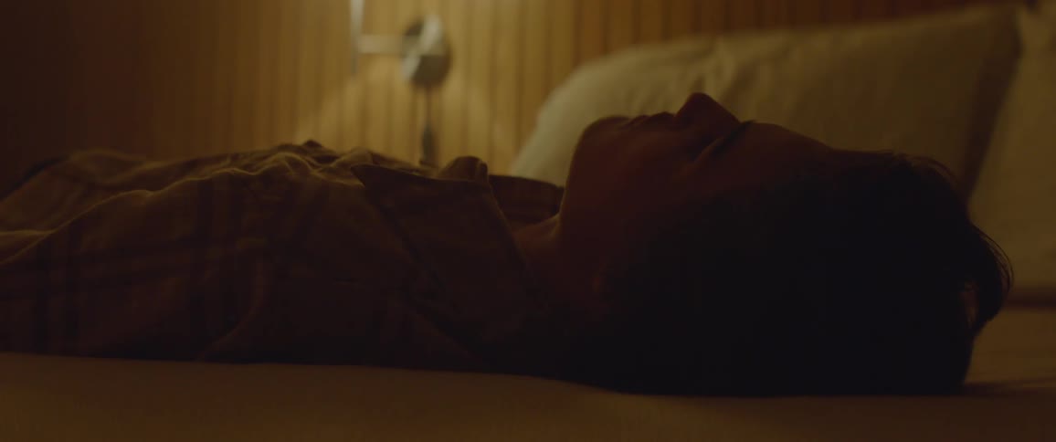 A man lays back on a hotel bed