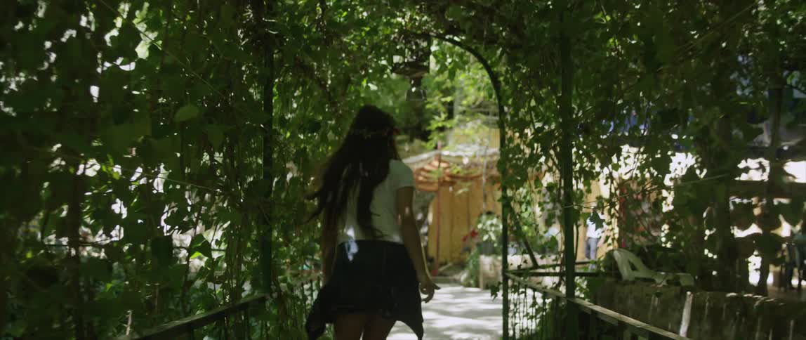A woman is walking through a garden towards a yard