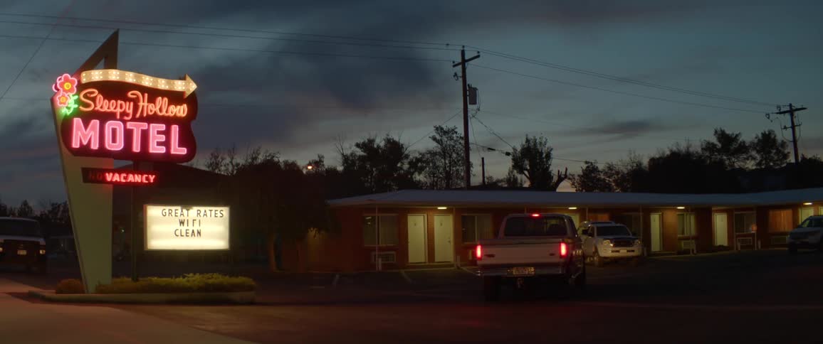 Neon lights illuminate a motel at night