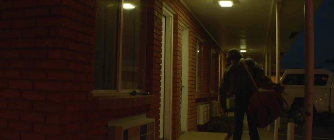 A man carries luggage to a motel room