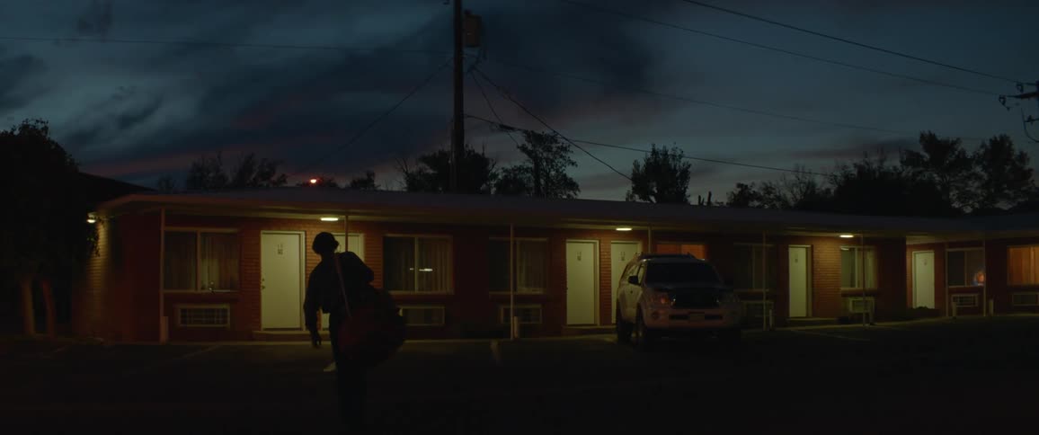 Man walks towards a motel at night