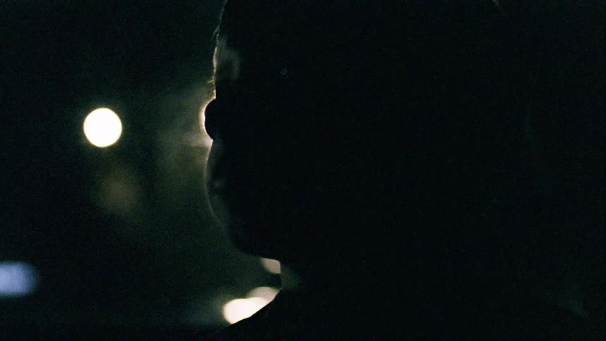 A young boy sits in a car as it drives at night