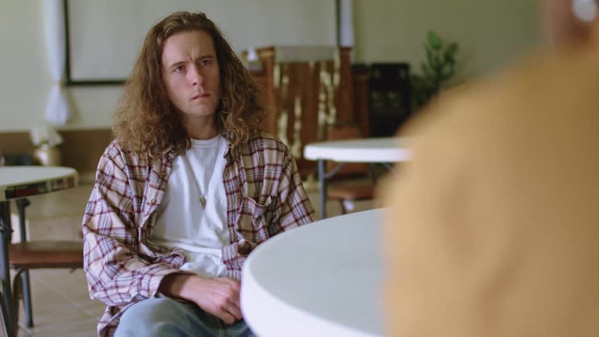 A teenager sits with an angry look on his face and listens to a teacher and then storms out of the room