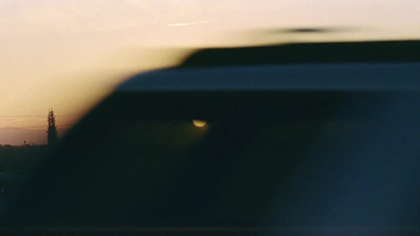 Cars driving down a street in front of a skyline