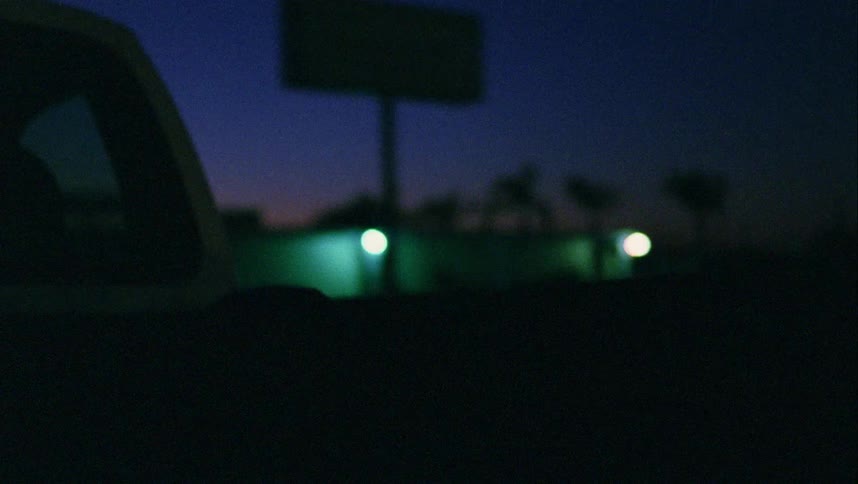 A teen sleeps in the back of a truck that is driving through a neighborhood