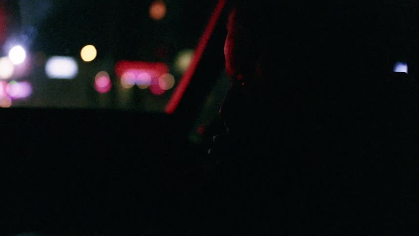 A woman sitting in a dark car at night